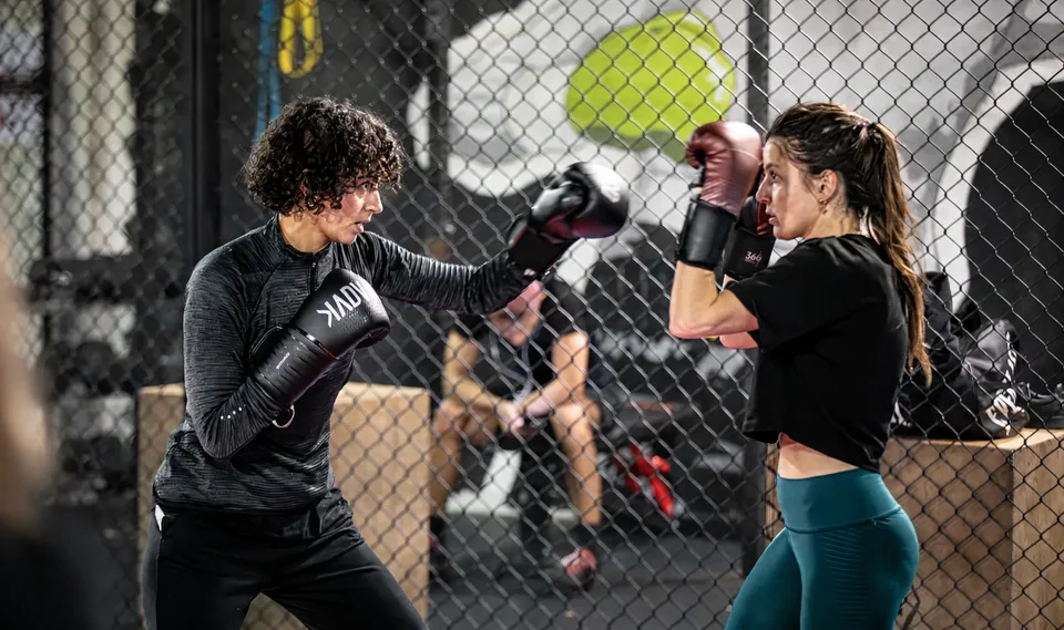 Cours de boxe femme près de Blagnac : deux boxeuses gantées travaillent leur garde face à face.