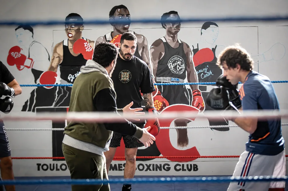 Salle de boxe proche de Blagnac : sur le ring de Boxing Center Toulouse Minimes, un entraîneur encadre deux boxeurs.